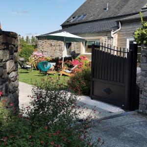 a house with a black fence and an umbrella at Aux Couleurs de la Baie in Cherrueix
