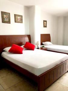 two beds with red pillows in a bedroom at Hotel Onix Gold in Guayaquil