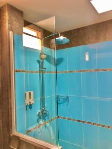 uma casa de banho em azulejos azuis com um chuveiro e um espelho. em Pana Long Beach Resort - SHA Plus em Ko Lanta