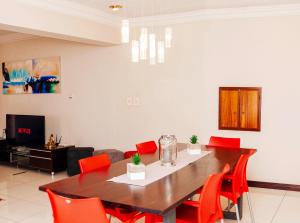 a dining room with a table and red chairs at KINGFISHER PLACE in Lenasia