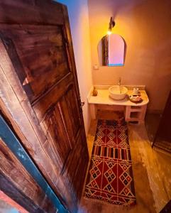 a bathroom with a wooden door and a sink at Aghurmi Siwa Ecolodge & Salt Cave in Siwa