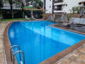 een groot zwembad met blauw water in een hotel bij Flat confortável ao lado da Paulista in Sao Paulo