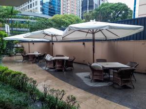 2 tafels en stoelen met parasols op een patio bij Flat confortável ao lado da Paulista in Sao Paulo