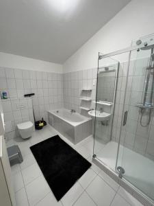 y baño con ducha, bañera y lavamanos. en Pannonia Appartements, en Bad Tatzmannsdorf