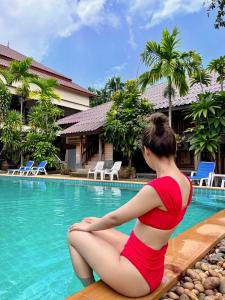 a woman sitting on a bench next to a swimming pool at Krabi Klong Muang Bay Resort in Klong Muang Beach