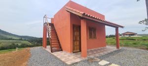 a small orange building with a staircase next to it at Pousada Colina das Maritacas in São Thomé das Letras