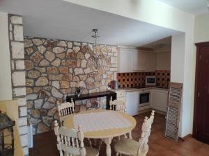 a kitchen with a stone wall with a table and chairs at Alkyon Villas in Syvota