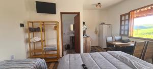 a bedroom with a bed and a desk and a refrigerator at Pousada Colina das Maritacas in São Thomé das Letras