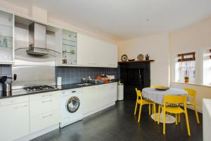 a kitchen with white cabinets and a table and yellow chairs at Luxury 2 Bedroom Apartment in London Bridge in London