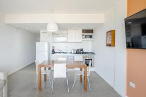 eine Küche mit einem Holztisch und weißen Geräten in der Unterkunft Departamento Apart Espacio Marina in Villa Gesell