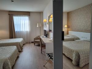 a hotel room with three beds and a desk with a computer at Hotel Datini in Prato