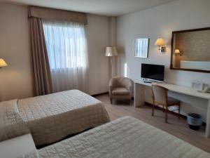 a hotel room with a bedroom with a desk and a bed at Hotel Datini in Prato