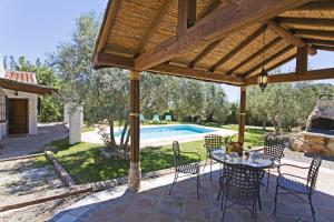 un patio con mesa y sillas y una piscina en Villa La Clavelina Rocabella, en El Chorro