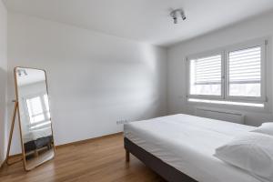 een witte slaapkamer met een bed en een spiegel bij Casa Bassani con terrazzo by Wonderful Italy in Bologna