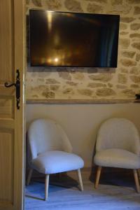 2 Stühle in einem Zimmer mit einem TV an der Wand in der Unterkunft Domaine Moulin de Quincenat Gîte Moulin au Bois Dormant in Champagnat