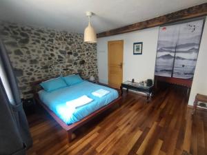 1 dormitorio con cama y pared de piedra en Les Chatougoulis en Les Bordes-sur-Lez
