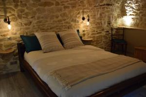 Cama en habitación con pared de piedra en Domaine Moulin de Quincenat Gîte Moulin au Bois Dormant, en Champagnat