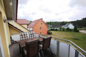 einen Balkon mit einem Holztisch und Stühlen in der Unterkunft Ferienwohnungen Seevogel in Ostseebad Koserow