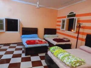 Habitación con 2 camas y suelo a cuadros. en Algaafary GeustHouse en Asuán