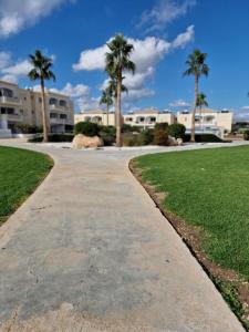a sidewalk in front of a building with palm trees at Escape and relax cozy apartment in Pafos! in Mandria