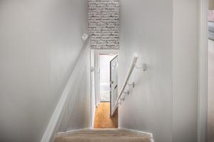 a staircase with white walls and a brick wall at Curb Properties - Super Apartment Moments From Town Centre in Cheltenham