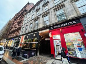 a newspoke store on a city street with people standing outside at Queen Street City Centre Apartment in Glasgow