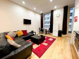 a living room with a black leather couch and a red rug at Queen Street City Centre Apartment in Glasgow