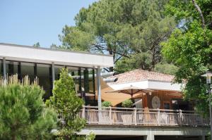 a house with a balcony with an umbrella at Domaine du Ferret Restaurant & Spa in Cap-Ferret