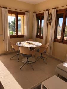 a living room with a table and chairs and windows at Casa Peppino in Teulada