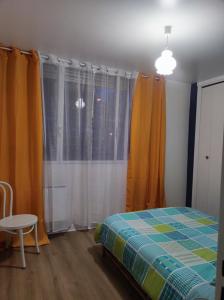 - une chambre avec un lit, des rideaux orange et une table dans l'établissement L'appart, à Limoges