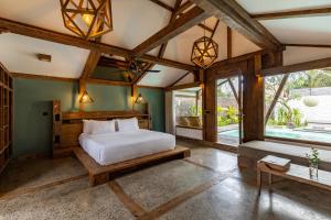 a bedroom with a bed and a large window at Kuno Villas in Gili Trawangan