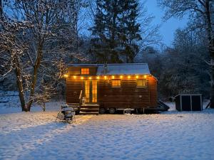 a wooden cabin in the snow with lights on it at Grimmwald Tiny House in Calden
