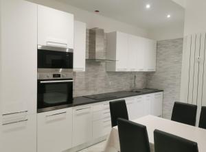 a kitchen with white cabinets and a table with chairs at Residenze Niguarda E in Milan