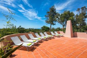 una fila de sillones blancos en un patio de ladrillo en Casa Monte Novo, en Lagoa