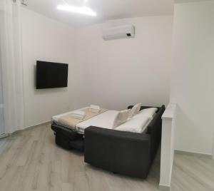 Cama negra en habitación blanca con TV de pantalla plana en Residenze Niguarda E, en Milán
