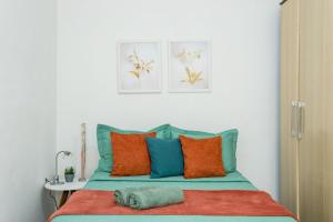 1 dormitorio con 1 cama con almohadas de color naranja y azul en Conforto e relax, caminhando para a Praia de Copacabana, Quarto e Sala, completo, com wi fi, cozinha, ar condicionado, en Río de Janeiro