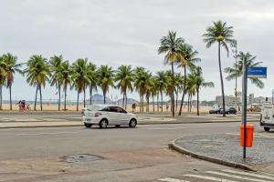 un coche blanco conduciendo por una calle con palmeras en Conforto e relax, caminhando para a Praia de Copacabana, Quarto e Sala, completo, com wi fi, cozinha, ar condicionado, en Río de Janeiro