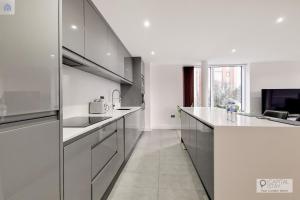 a kitchen with white counters and stainless steel appliances at Stylish Three Bedroom Apartment by London ExCeL in London