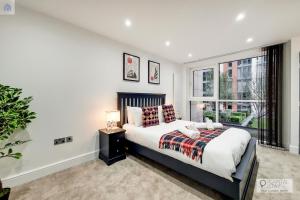 a bedroom with a bed and a large window at Stylish Three Bedroom Apartment by London ExCeL in London