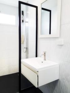 une salle de bains blanche avec un lavabo et un miroir dans l'établissement Doodle Lodge Chiang Mai, à Chiang Mai