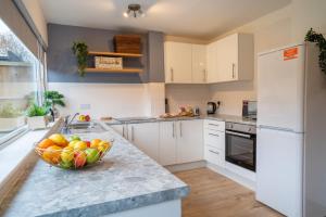 una cocina con un bol de fruta en una barra en Saltbox Stays- 3 bed house with off-street parking, sleeps 6 en Newhall