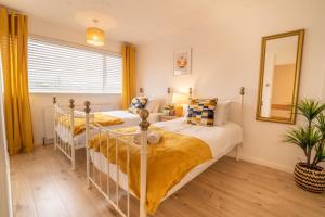 1 dormitorio con 2 camas y espejo en Saltbox Stays- 3 bed house with off-street parking, sleeps 6 en Newhall