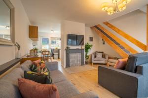 a living room with a couch and a tv at Saltbox Stays- 3 bed house with off-street parking, sleeps 6 in Newhall