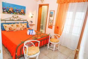 - une chambre dotée d'un lit avec des draps orange et des chaises dans l'établissement B&B La Strea, à Porto Cesareo