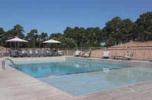 a swimming pool with chairs and umbrellas on a wooden deck at Domaine du Ferret Restaurant & Spa in Cap-Ferret