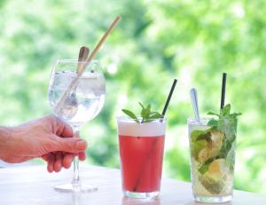 a person holding a wine glass next to two cocktails at Domaine du Ferret Restaurant & Spa in Cap-Ferret