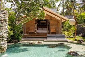 a resort with a pool and a room with a bed at Kuno Villas in Gili Trawangan