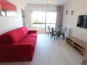 a living room with a red couch and a table at Appartement T2 à Bénodet, refait à neuf, balcon, plage à pied, parking, classé 2 étoiles - FR-1-481-64 in Bénodet