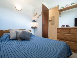 Cette chambre comprend un lit avec des draps bleus et une télévision. dans l'établissement Appartement Saint-Lary-Soulan, 3 pièces, 6 personnes - FR-1-296-315, à Saint-Lary-Soulan