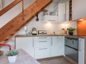 a kitchen with white cabinets and a staircase at Duplex rénové pour 4 à Saint-Lary près des pistes et commodités - FR-1-296-300 in Saint-Lary-Soulan +6 photos